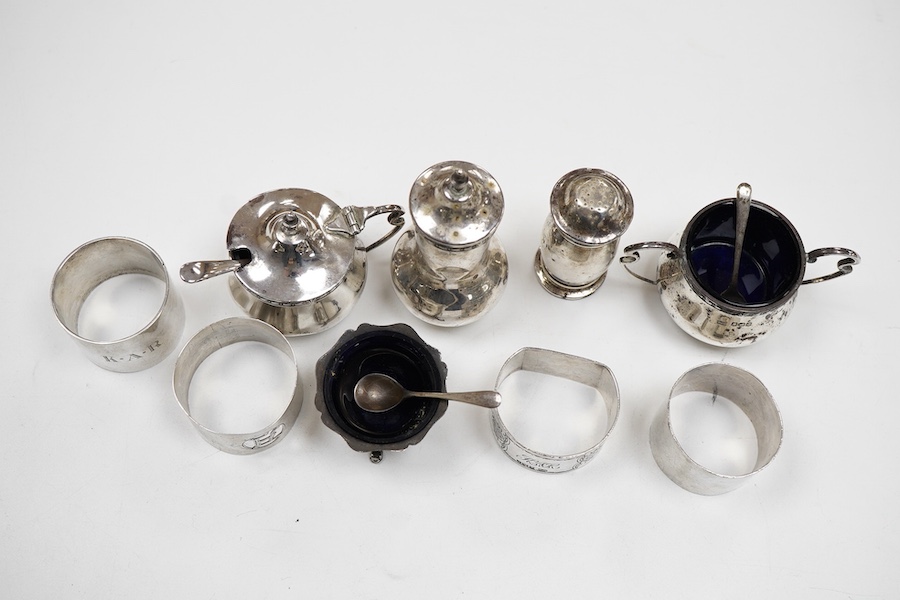 A George V silver three piece condiment set by Walker & Hall, Sheffield, 1921, together withy two other silver condiments, three assorted silver condiment spoons and four assorted silver napkin rings.
